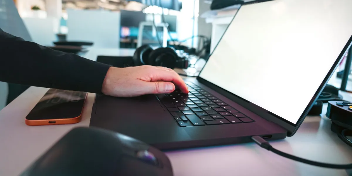 In einem eleganten Büroambiente tippt man von Hand auf einer Laptop-Tastatur und präsentiert dabei moderne Technologie.