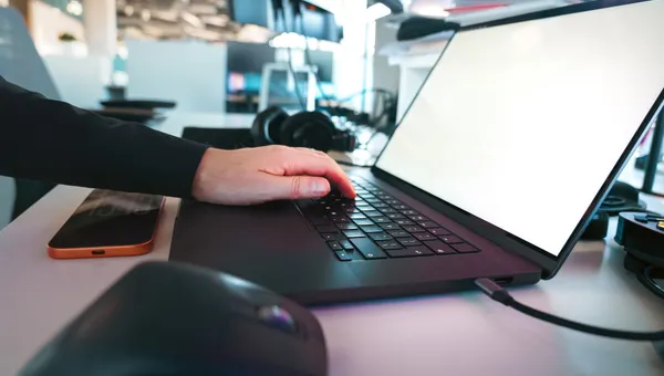 In einem eleganten Büroambiente tippt man von Hand auf einer Laptop-Tastatur und präsentiert dabei moderne Technologie.